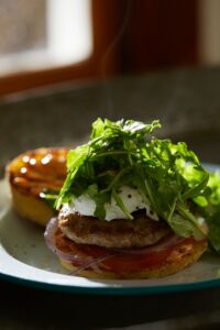 a breakfast sandwich with sausage egg tomato and greens